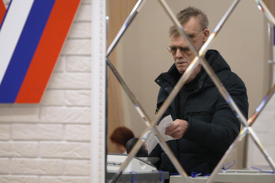 Un hombre se ve reflejado en un espejo mientras vota en un centro electoral durante las elecciones presidenciales rusas, el sábado 16 de marzo de 2024, en San Petersburgo, Rusia. (AP Foto/Dmitri Lovetsky)