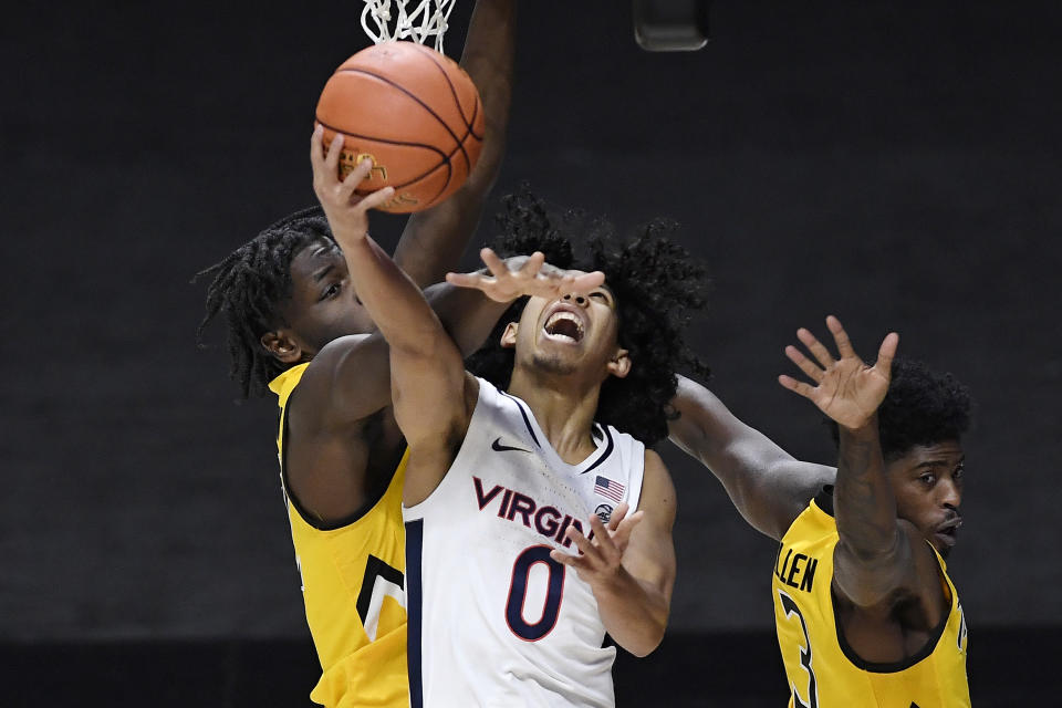 Virginia's Kihei Clark, center, is fouled by Towson's Charles Thompson, left, as Towson's Cam Allen, right, defends in the second half of an NCAA college basketball game, Wednesday, Nov. 25, 2020, in Uncasville, Conn. (AP Photo/Jessica Hill)