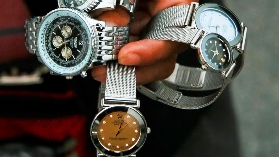 SHANGHAI, CHINA - OCTOBER 28: A Chinese salesman shows his merchandise of fake designer watches on the Bund in Shanghai, on October 28, 2007.