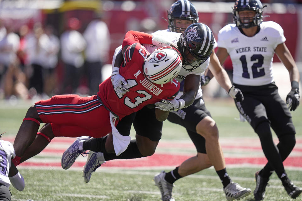 Weber State linebacker Winston Reid, rear, tackles Utah quarterback Nate Johnson (13) during the first half of an NCAA college football game Saturday, Sept. 16, 2023, in Salt Lake City. (AP Photo/Rick Bowmer)