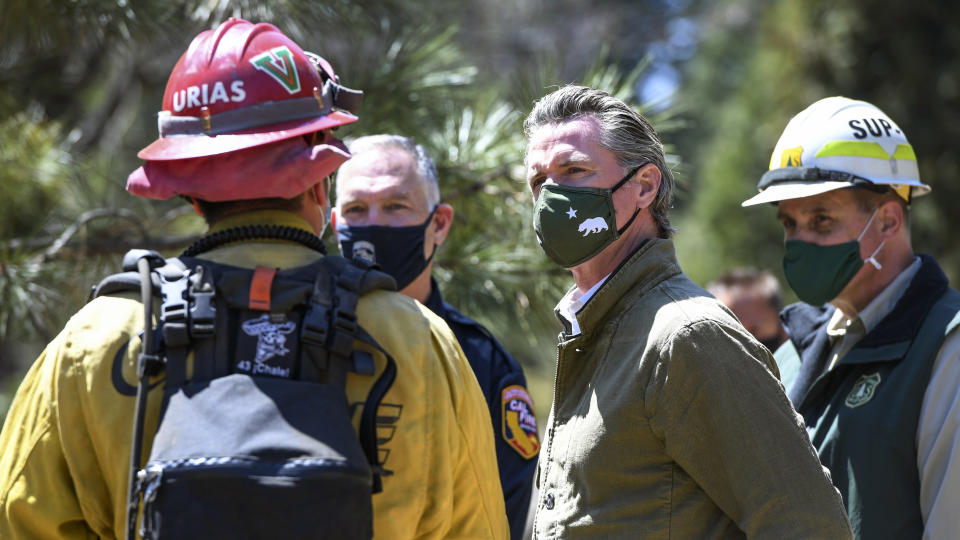 Gov. Gavin Newsom talks with local and state fire officials while touring an area burned by last year's Creek Fire near Shaver Lake in Fresno County, Calif., Thursday, April 8, 2021. California will authorize $536 million for wildfire mitigation and forest management projects before the worst of the fire season strikes later this year, Newsom and legislative leaders said. (Craig Kohlruss/The Fresno Bee via AP)