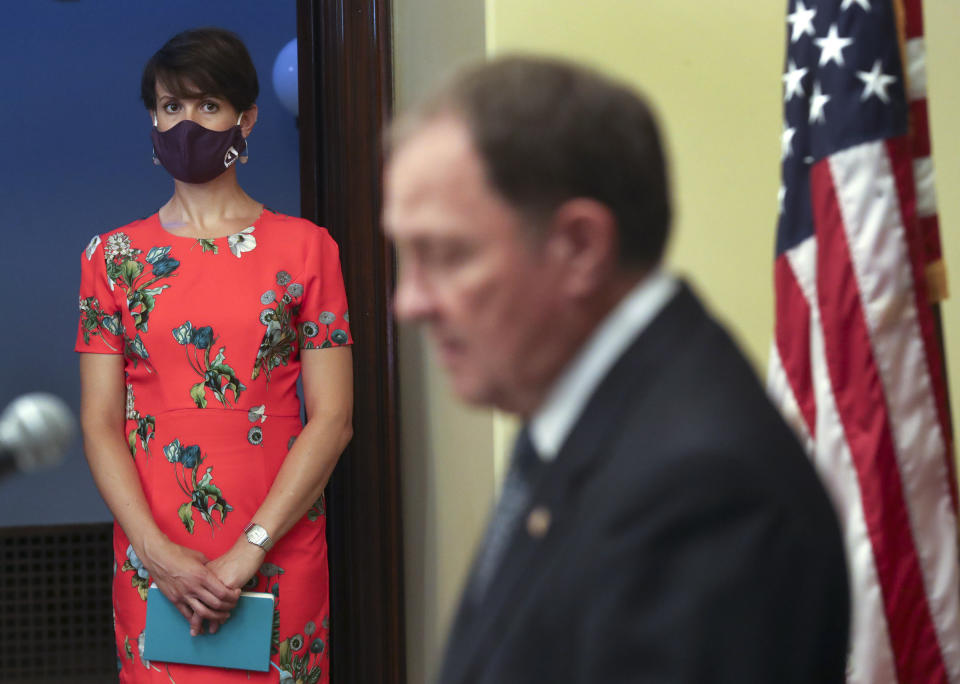 Dr. Angela Dunn, state epidemiologist with the Utah Department of Health, listens to Gov. Gary Herbert as he speaks during the weekly COVID-19 briefing at the Capitol in Salt Lake City on Wednesday, Aug. 26, 2020. The High school seniors who pushed back against recent anti-mask protests joined Gov. Gary Herbert at a weekly briefing imploring parents to stop fighting Utah's face covering mandate in schools. Three Enterprise High School students voiced frustration with parents and other community members who recently planned a no-mask protest Monday, Aug. 24, 2020, in St. George. (Steve Griffin/Deseret News, via AP, Pool)