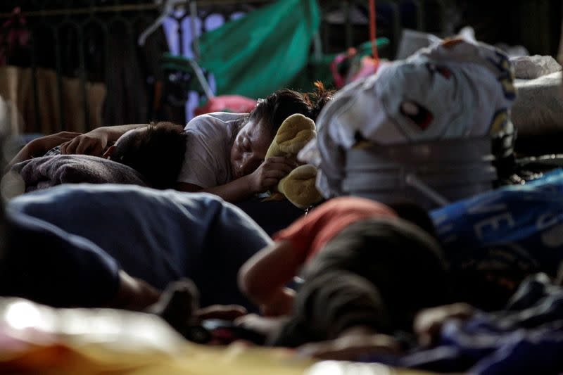 Migrantes solicitantes de asilo, que fueron aprehendidos y devueltos a México bajo el Título 42 después de cruzar la frontera de México a Estados Unidos, descansan en una plaza pública donde cientos de migrantes viven en tiendas de campaña, en Reynosa, México