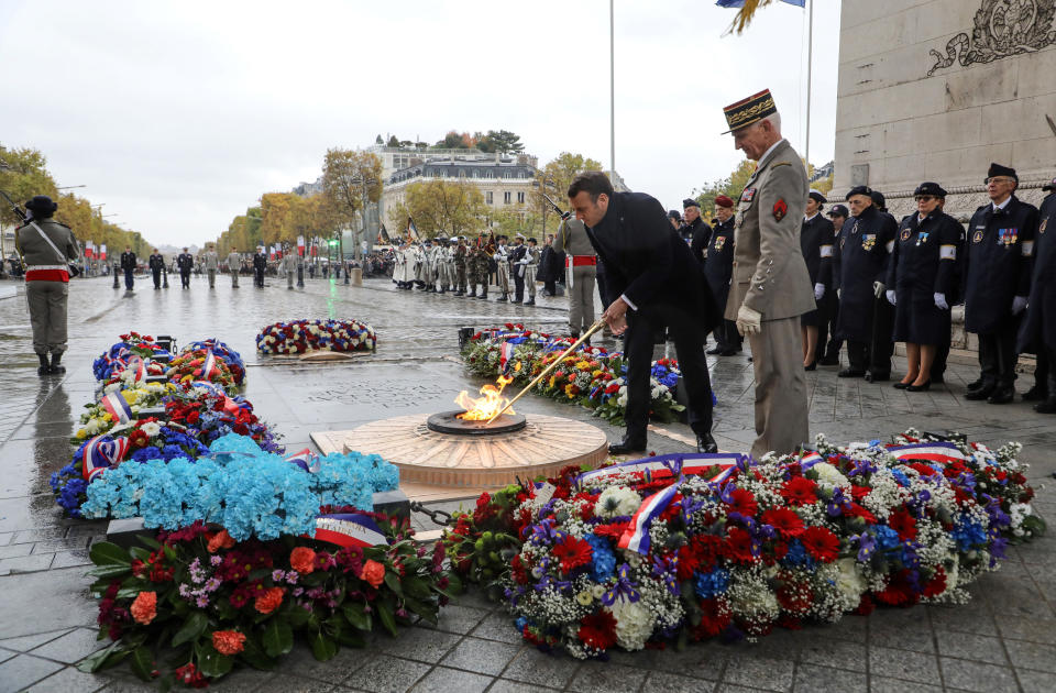 French President Emmanuel Macron lights up the flame at the tomb of the unknown soldier next to French Armies Chief of Staff General Francois Lecointre under the Arc de Triomphe during commemorations marking the 101st anniversary of the 1918 armistice, ending World War I, in Paris Monday Nov. 11, 2019 . (Ludovic Marin/Pool via AP)