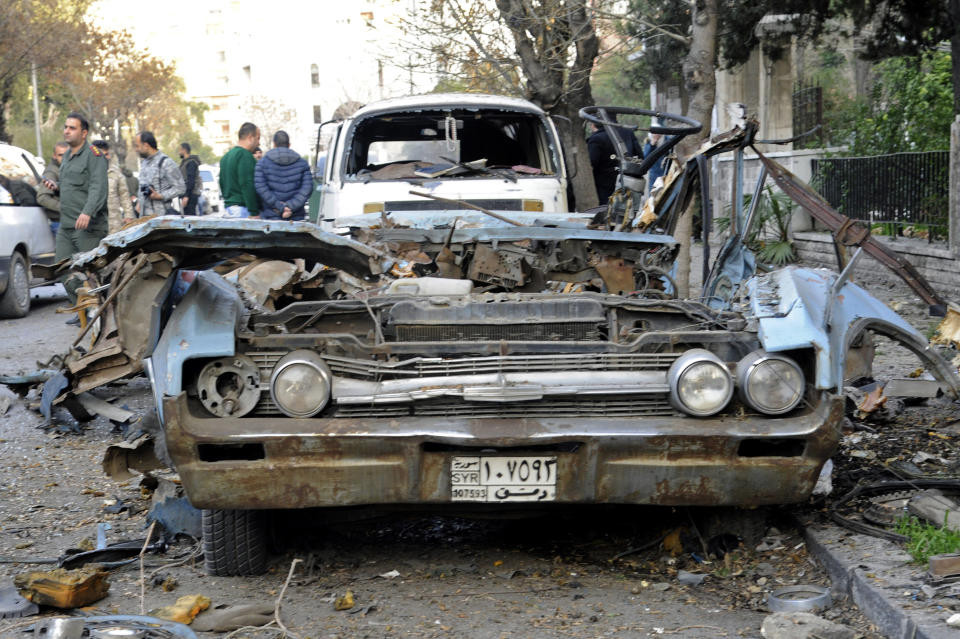 In this photo released by the Syrian official news agency SANA, people gather at the site of an explosion in the Adawi neighborhood of Damascus, Syria, Thursday, Jan. 24, 2019. Syrian state media reported that the bomb caused property damage but no casualties. The Russian Embassy is located several hundred meters (yards) away. (SANA via AP)