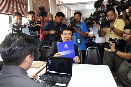 Somchai Srisuthiyakorn (C) Election commissioner holds up a document during filing the charges against members of a Facebook group based in Thailand's northeastern province of Khon Kaen at a police station in Bangkok, Thailand, April 27, 2016. Dailynews/Handout via REUTERS