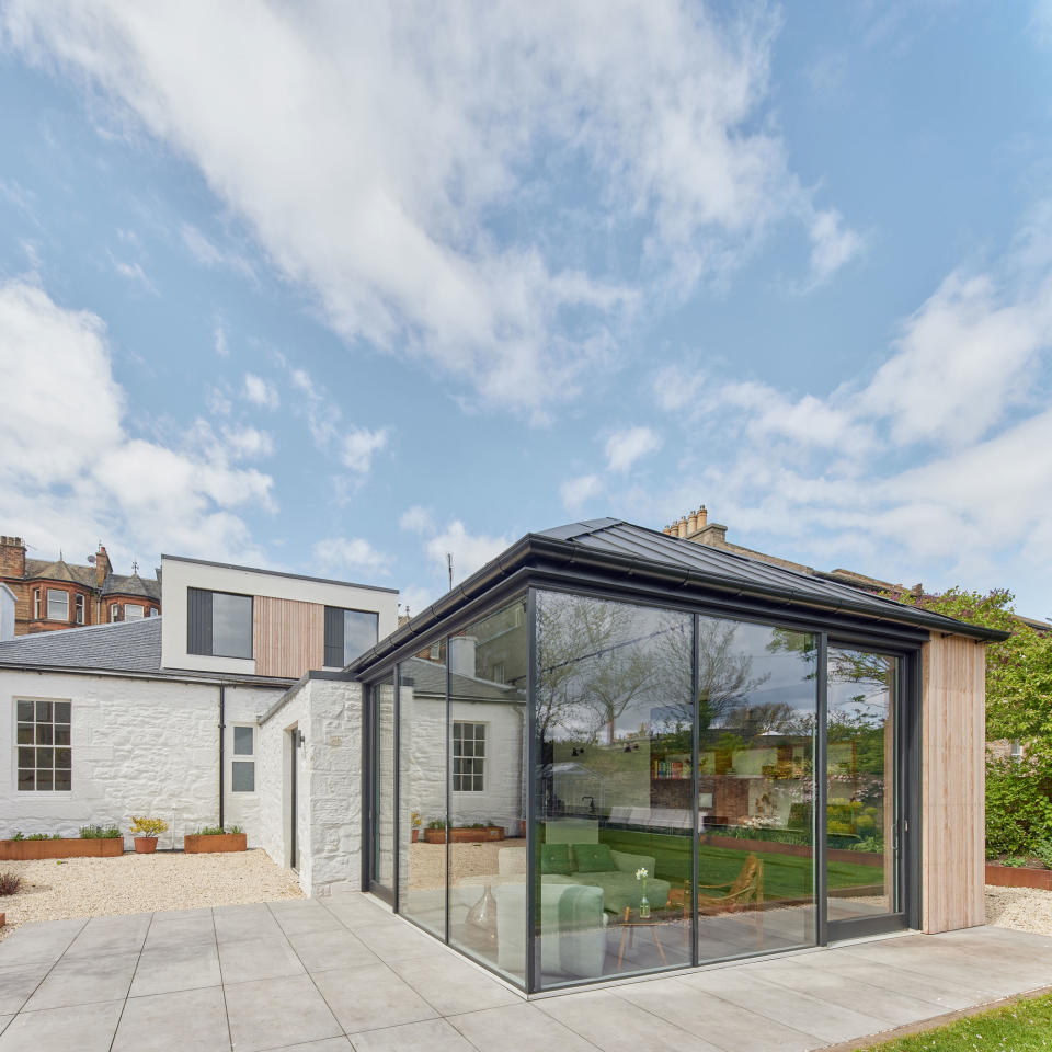 exterior view of a sunny corner glazed extension with an armchair