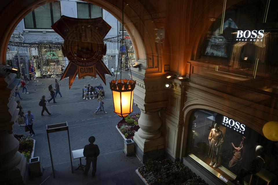 A member of security stands at an entrance inside the GUM department store where many of branded boutiques are closed due to sanctions in Moscow, Russia, Tuesday, Aug. 9, 2022. Often, it's hard to tell when stores are closed. At the famous GUM department store lined with shops in Red Square, most of the closed storefronts still had the lights on and a clerk or guard inside. (AP Photo/Alexander Zemlianichenko)