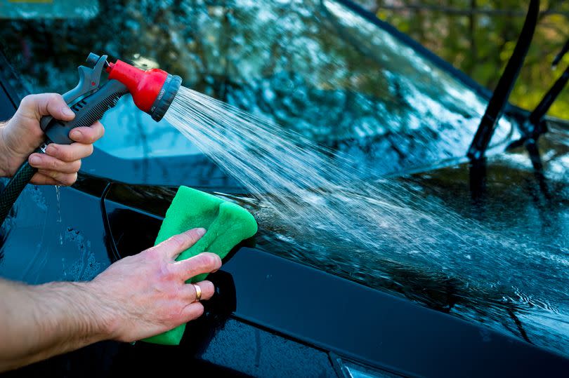 Closeup picture, image young woman, driver, dry wiping her car with microfiber cloth after washing it, cleaning auto, automobile windows. Transportation self service, care concept. Paint protection