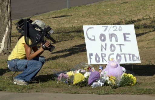 A cameraman takes video of a memorial for victims near the movie theater where 12 people were killed July 20, in Aurora, Colorado. Police on Saturday studied ways to enter an apartment rigged with explosives belonging to the man believed to have killed 12 moviegoers at an opening of the latest Batman movie