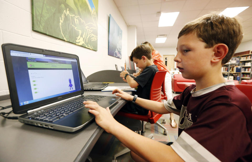 In this May 8, 2019, photo, third-grade student Miles Stidham uses an East Webster High School laptop to do homework in Maben, Miss. The Stidhams are unable to get internet at their home in the country, so they take advantage of the internet in the school's library. (AP Photo/Rogelio V. Solis)