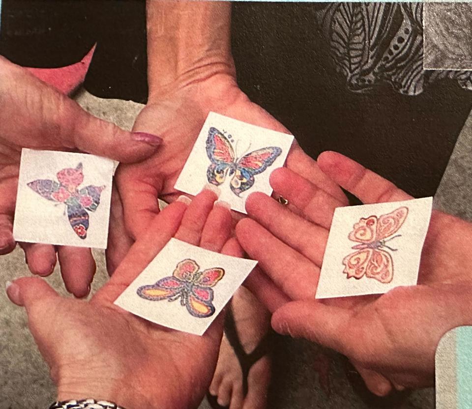 The author, her sisters, and her mom holding the temporary butterfly tattoos they got on a trip for Ilyse's 50th birthday.