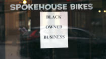 In this Wednesday, June 24, 2020, photograph, a sign in the window informs passersby that Spokehouse Bikes in the Upham's Corner neighborhood of Boston is a Black-owned business. Many from outside Boston have donated to and shopped at the store which was robbed and vandalized earlier in the month. (AP Photo/Charles Krupa)