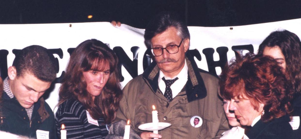 People hold candles at a vigil.