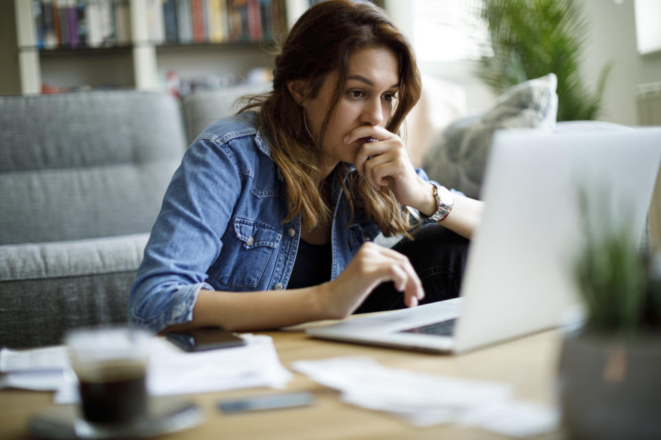 Person looking at laptop screen with focused expression, in a home office setting