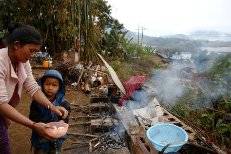 Refugee who fled fighting in neighbouring Myanmar washes dishes outside the house of a relative in the village of Baiyan near Nansan in the Yunnan province, China, March 12, 2017. REUTERS/Thomas Peter