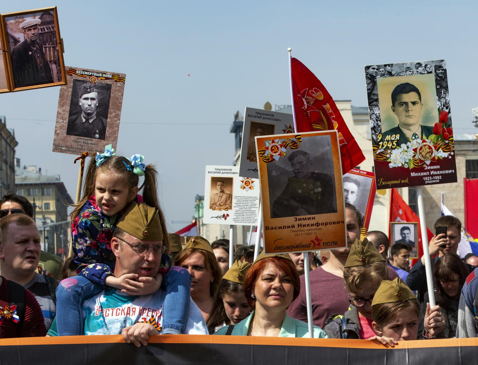 People carry portraits of relatives who fought in World War II, and Soviet flags, during the Immortal Regiment march through the main street toward Red Square in Moscow, Russia, Thursday, May 9, 2019, celebrating 74 years since the end of WWII and the defeat of Nazi Germany. (AP Photo/Dmitry Serebryakov)