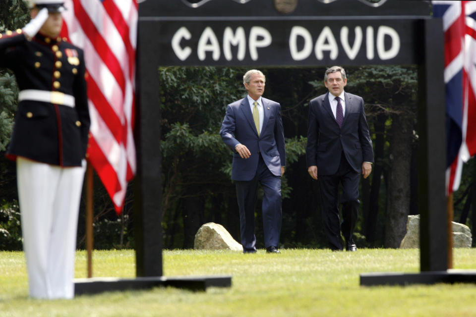 FILE - President George W. Bush, left, and British Prime Minister Gordon Brown walk to a joint press availability at Camp David, Md., July 30, 2007. (AP Photo/Charles Dharapak, File)