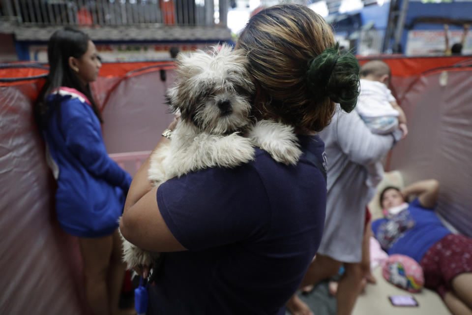 A resident carries her dog inside an evacuation center as rains from a typhoon locally known as Goni start to pour in Manila, Philippines on Sunday, Nov. 1, 2020. A super typhoon slammed into the eastern Philippines with ferocious winds early Sunday and about a million people have been evacuated in its projected path, including in the capital where the main international airport was ordered closed. (AP Photo/Aaron Favila)