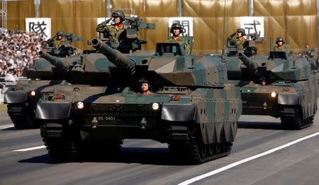 Members of a tank unit of Japan's Self-Defense Forces (SDF) riding on Type-10 armoured tanks take part in a military review during the annual troop review ceremony at Asaka Base in Asaka, near Tokyo October 27, 2013. REUTERS/Issei Kato/File Photo