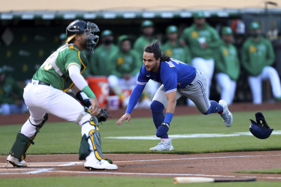Toronto Blue Jays' Bo Bichette dives for home as Oakland Athletics' Austin Allen waits for the throw during the first inning of a baseball game in Oakland, Calif., Wednesday, May 5, 2021. (AP Photo/Jed Jacobsohn)