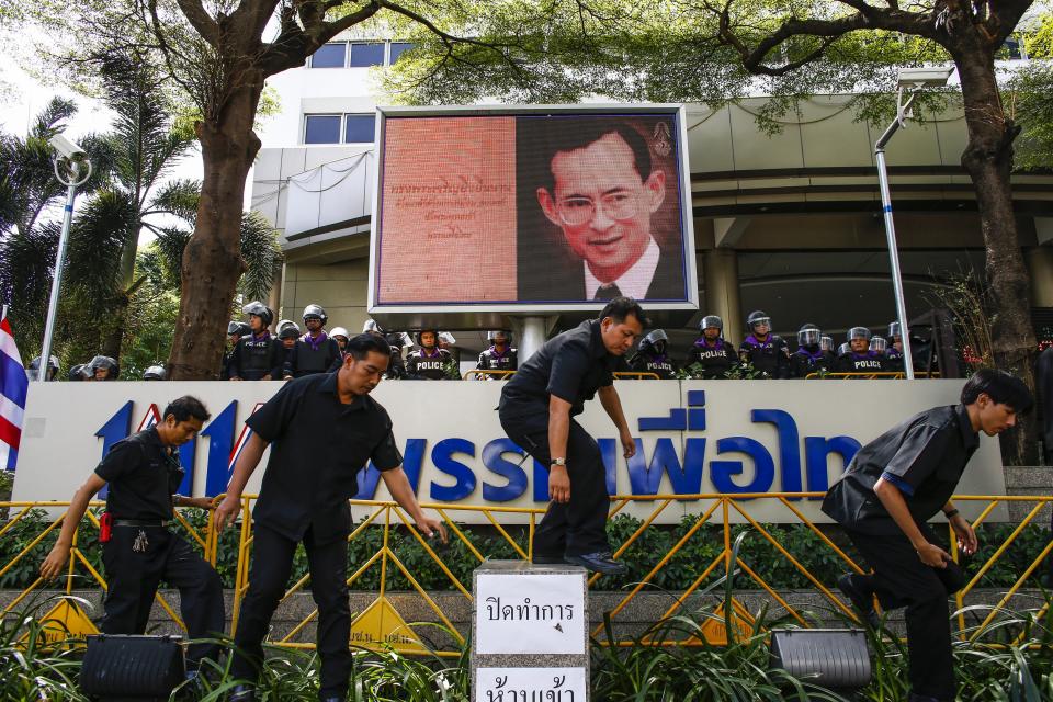 Security guards install barricades as riot policemen stand guard at the headquarters of the ruling Puea Thai Party of Prime Minister Yingluck Shinawatra in Bangkok