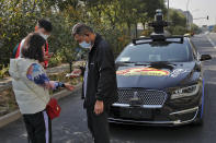 A couple wearing face masks to help curb the spread of the coronavirus gets temperature check before they try out the self-driving ride-hailing services by tech giant Baidu on the outskirts of Beijing on Oct. 15, 2020. Chinese leaders are shifting focus from the coronavirus back to long-term goals of making China a technology leader at this year's highest-profile political event, the meeting of its ceremonial legislature, amid tension with Washington and Europe over trade, Hong Kong and human rights. (AP Photo/Andy Wong)