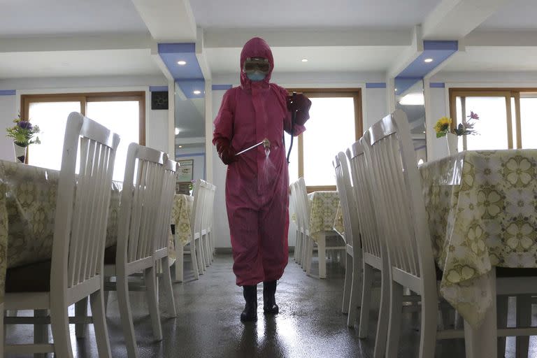 Un empleado de la Fábrica de Productos de Higiene Dental de Pyongyang desinfecta el suelo de un comedor mientras el Estado aumenta las medidas para detener la propagación de enfermedades en Pyongyang, Corea del Norte, el lunes 16 de mayo de 2022.