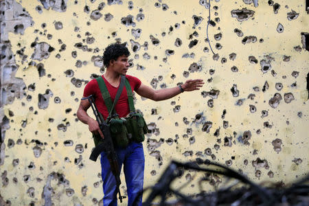 A member of the joint Palestinian security force stands in front of a bullet-riddled wall inside the Ain el-Hilweh refugee camp near Sidon, southern Lebanon, April 13, 2017. REUTERS/Ali Hashisho