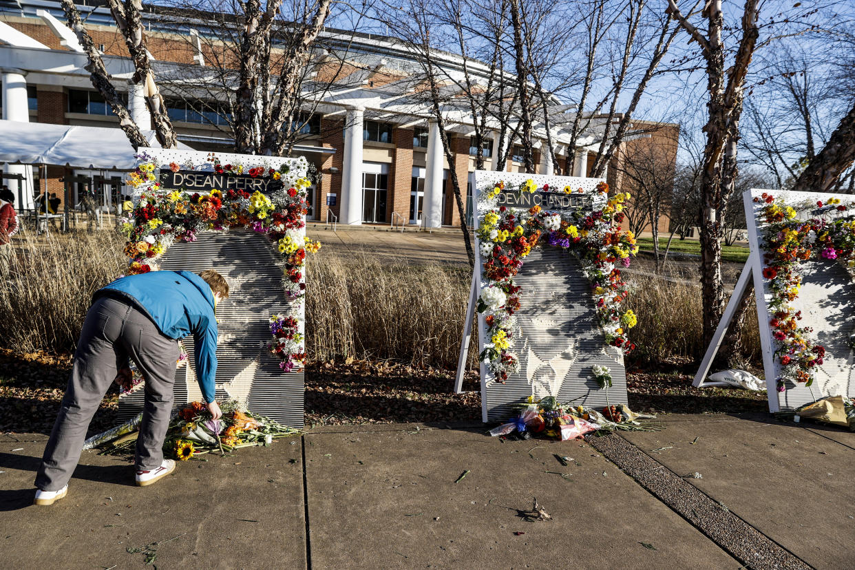 Ross Brown places flowers on a memorial for three slain University of Virginia football players on Saturday, Nov. 19, 2022, at John Paul Jones Arena on the university's campus in Charlottesville, Va. On Sunday, Nov. 13, University of Virginia football players Devin Chandler, Lavel Davis Jr. and D'Sean Perry were shot and killed by a teammate following a school field trip to Washington. (Shaban Athuman/Richmond Times-Dispatch via AP)