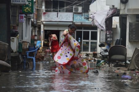 People clean a flooded street after typhoon Lekima hit Linhai