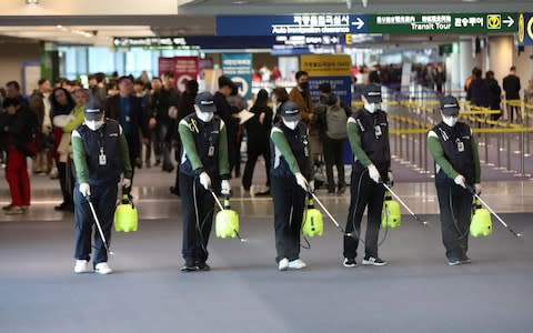 Workers spray antiseptic solution on the arrival lobby amid rising public concerns over the possible spread of a new coronavirus at Incheon International Airport in Incheon, South Korea - Credit: Suh Myung-geon/Yonhap