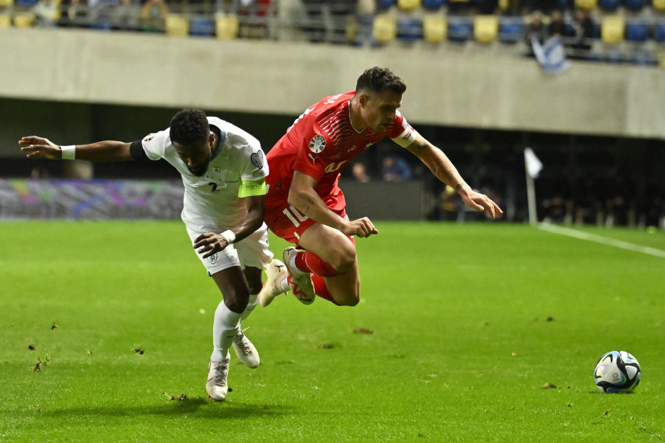 Israel's Eli Dasa, left, challenges Switzerland's Granit Xhaka during the Euro 2024 group I qualifying soccer match between Israel and Switzerland at the Pancho Arena in Felcsut, Hungary, Wednesday, Nov. 15, 2023. (AP Photo/Denes Erdos)