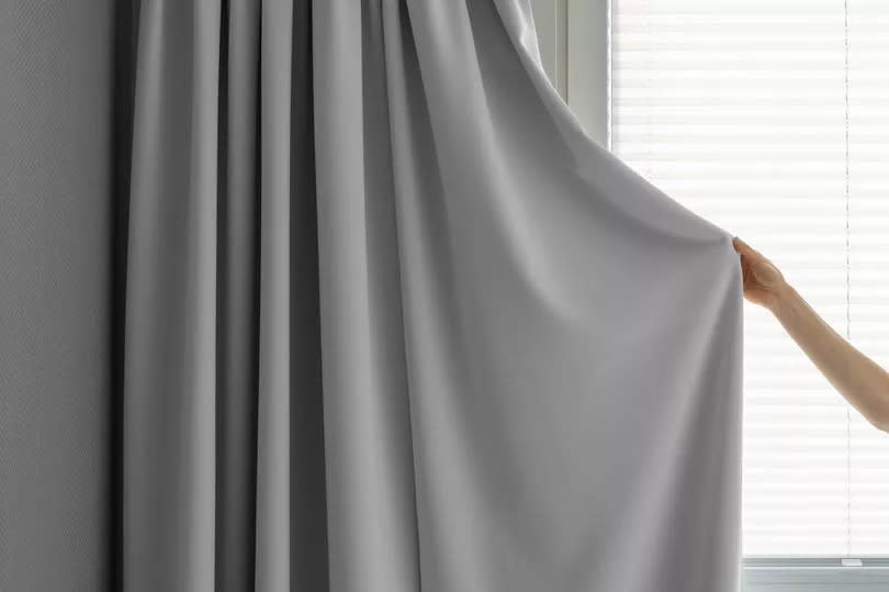 Female hold grey fabric curtain.