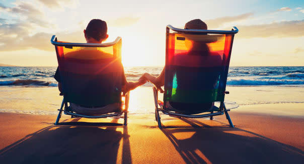 senior couple of old man and woman sitting on the beach watching sunset