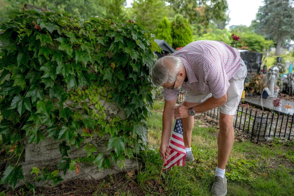 Volunteer John Hill replaces a flag at Cranston's Oakland Cemetery.