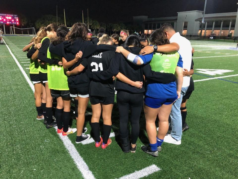 Somerset Canyons players huddle with coach Oscar Narvaez before Friday night's District 13-4A girls soccer semifinal against North Broward Prep.