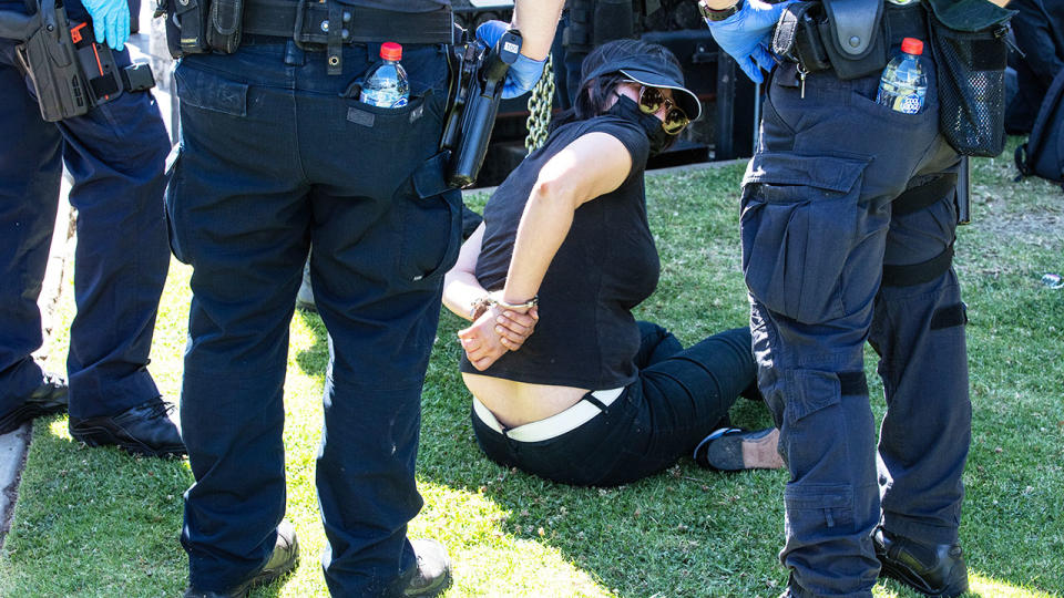 A protester, pictured here being detained outside of the Flemington racecourse.