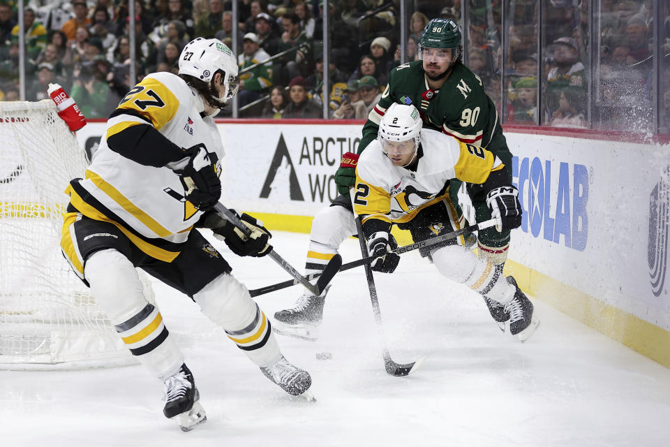 Minnesota Wild left wing Marcus Johansson (90) and Pittsburgh Penguins defenseman Chad Ruhwedel (2) compete for the puck while Penguins defenseman Ryan Graves, left, watches during the third period of an NHL hockey game Friday, Feb. 9, 2024, in St. Paul, Minn. (AP Photo/Matt Krohn)