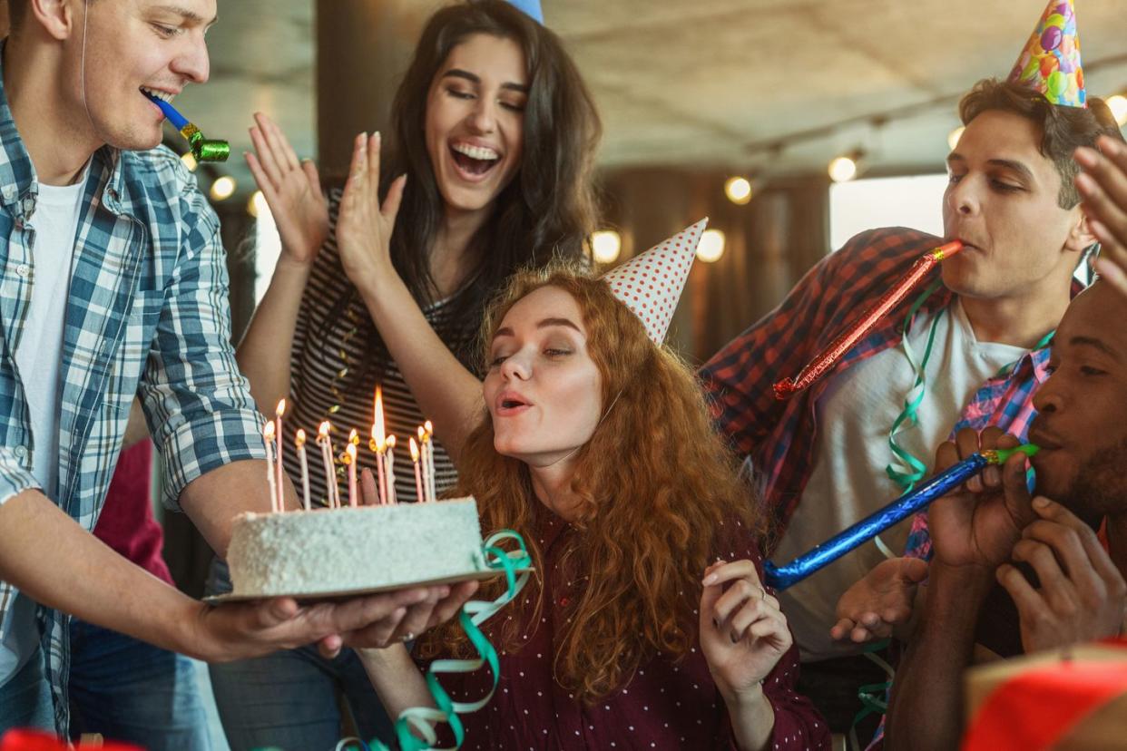 happy birthday girl is blowing candles on holiday cake and making wish