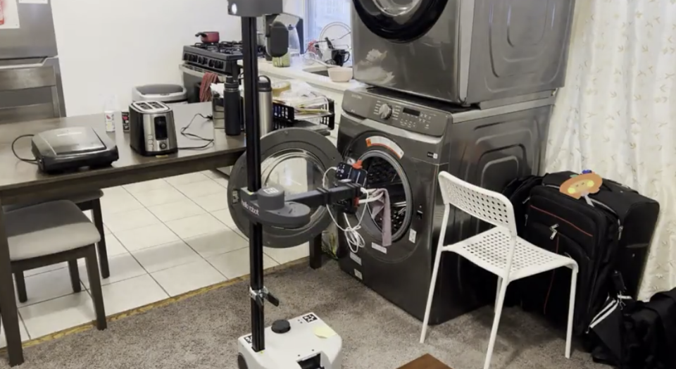 The Dobb-E robot carries a sock into the washer dryer (Dobb-E) 