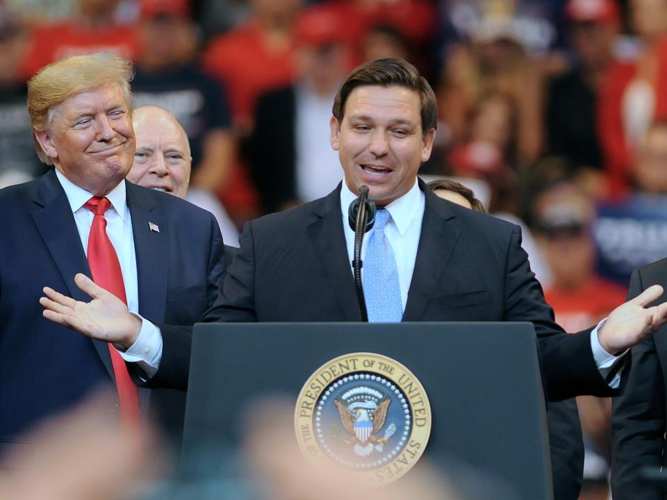 DeSantis speaking at podium next to Trump