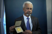 Abdulrazak Gurnah, a Tanzanian-born novelist and emeritus professor who lives in the UK, poses for photographs with his 2021 Nobel Prize for Literature medal after being presented it by the Ambassador of Sweden Mikaela Kumlin Granit in a ceremony at the Swedish Ambassador's Residence in London, Monday, Dec. 6, 2021. The 2021 Nobel Prize ceremonies are being reined in and scaled-down for the second year in a row due to the coronavirus pandemic, with the laureates receiving their Nobel Prize medals and diplomas in their home countries. (AP Photo/Matt Dunham)