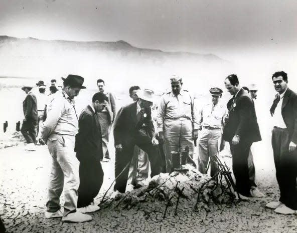 GROUND ZERO INSPECTION: Workers at the site of the first atomic bomb explosion are shown in this government file photo inspecting ground zero after the July 16, 1945, blast. J. Robert Oppenheimer, director of the bomb project, is third from left. Shown is what remained after the explosion of a 100-foot tower, atop which the bomb sat before detonation.