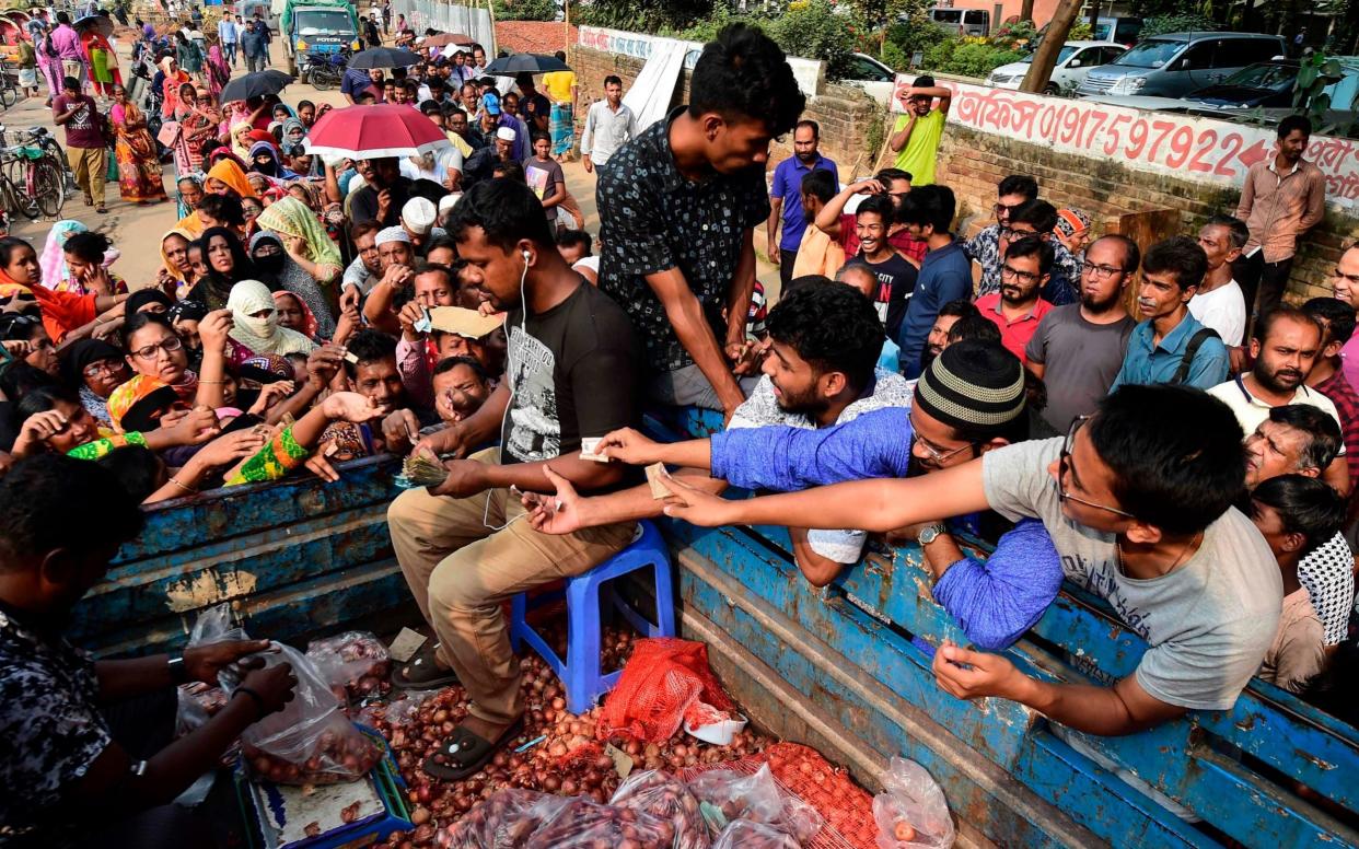 People scuffle as they purchase subsidised onions in Dhaka  - AFP