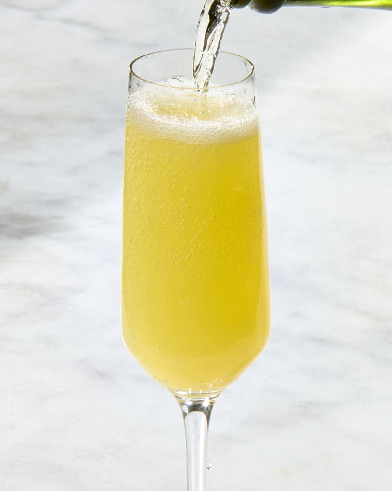 head on shot of a mimosa being poured in a flute glass