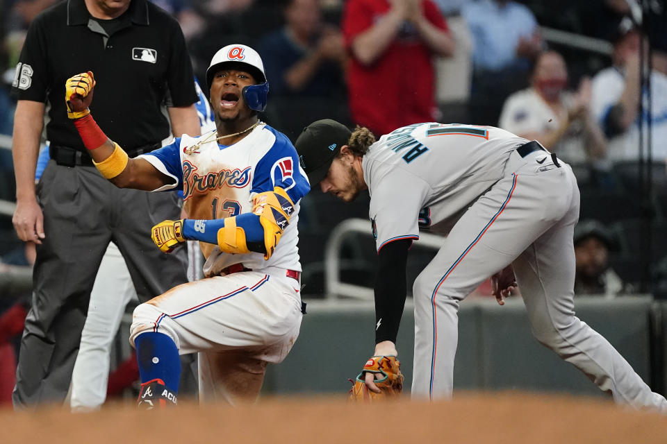 Atlanta Braves' Ronald Acuna Jr. (13) reacts after sliding into third base with a triple as Miami Marlins third baseman Brian Anderson, right, handles a late throw in the third inning of a baseball game Monday, April 12, 2021, in Atlanta. (AP Photo/John Bazemore)