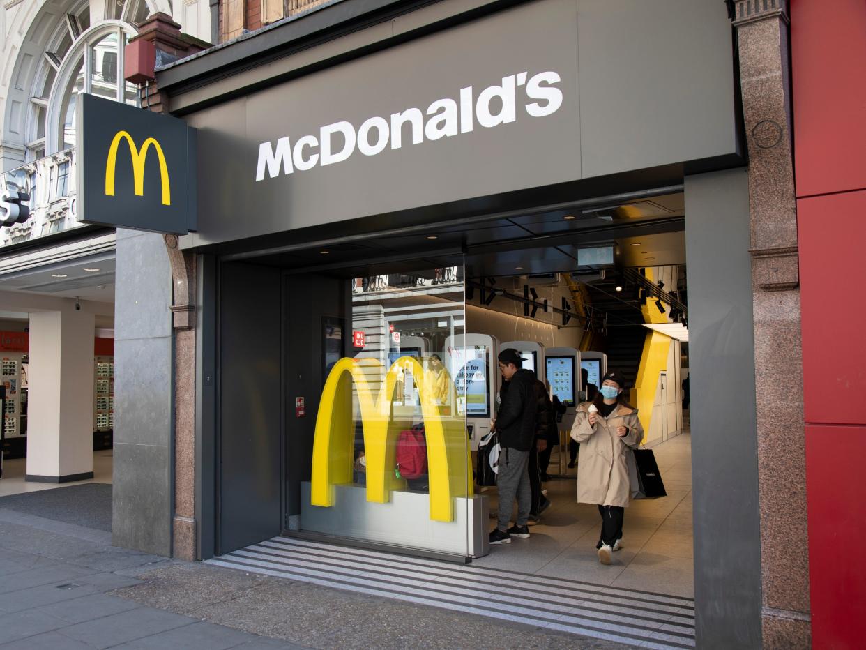 Woman wearing a face mask leaves McDonalds with her McFlurry on Oxford Street in March 2020