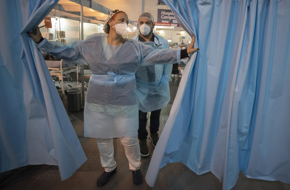 A health worker opens the curtain that separates the emergency unit inside a field hospital that treats COVID-19 patients in Ribeirao Pires in the greater Sao Paulo area of Brazil, Tuesday, April 13, 2021. (AP Photo/Andre Penner)