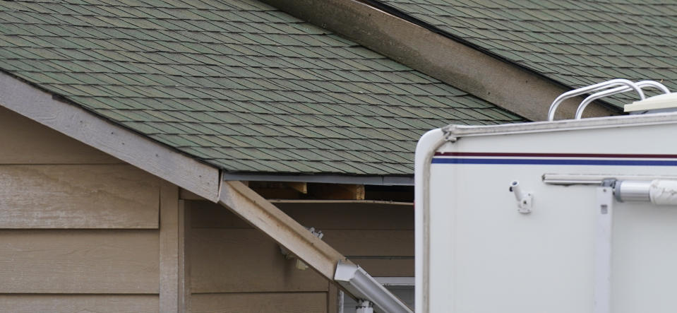 The rain gutter on the home of Kirby Klements hangs down after a piece of debris from an airplane crushed his pickup truck parked next to the home in Broomfield, Colo., as the plane shed parts while making an emergency landing at nearby Denver International Airport Saturday, Feb. 20, 2021. (AP Photo/David Zalubowski)